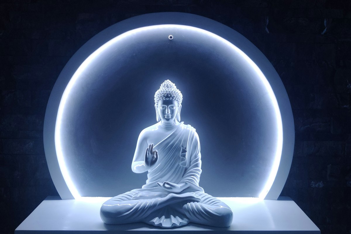 Buddha statue meditating in front of a glowing golden halo